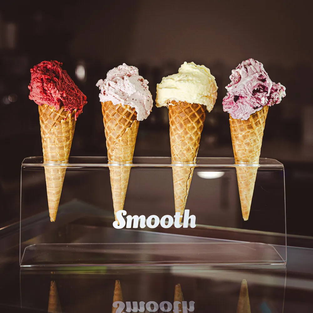 Four waffle cones in a Smooth cone stand, each topped with a different scoop of gelato.