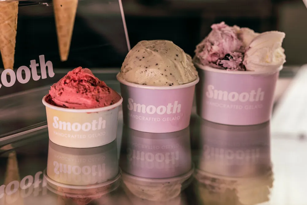 Three tubs of gelato lined up on the counter, a scoop resting on each.