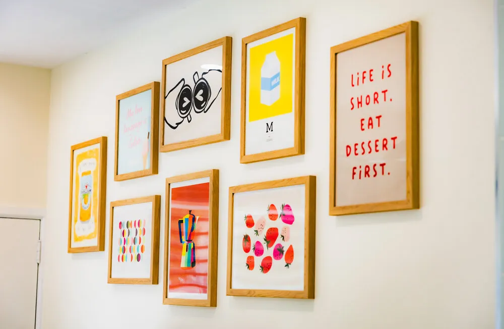 The shop's gallery wall — framed prints including one reading 'Life is short, eat dessert first'.